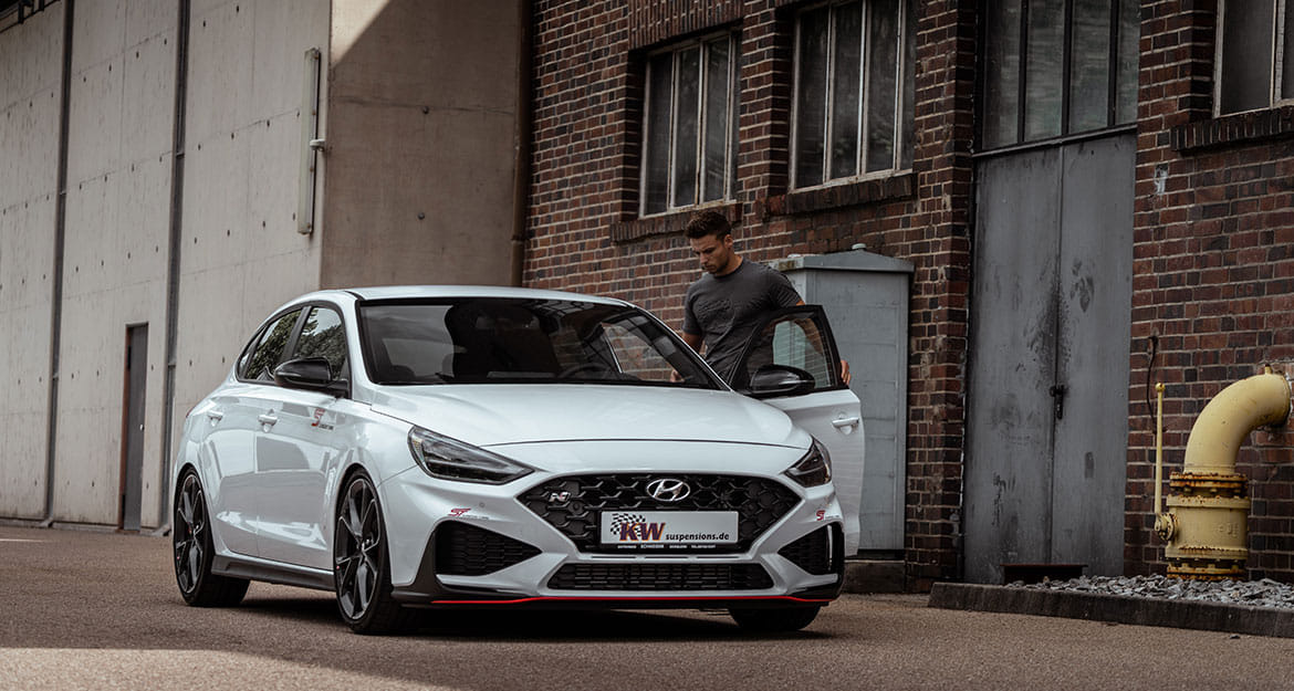 Young man gets into a white Hyundai i30 N equipped with KW V3 coilovers